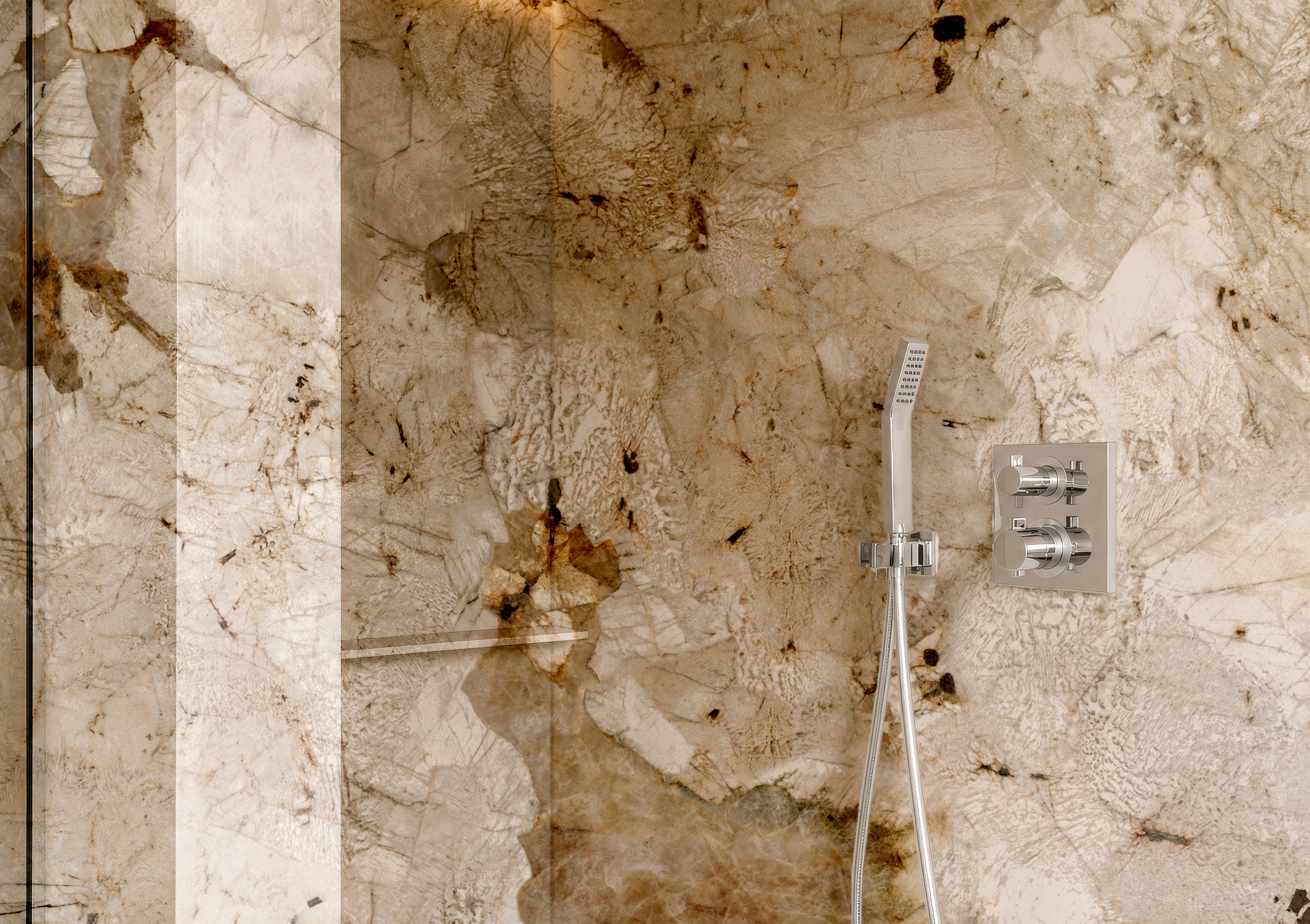 A shower wall in large-format stone with a hand shower