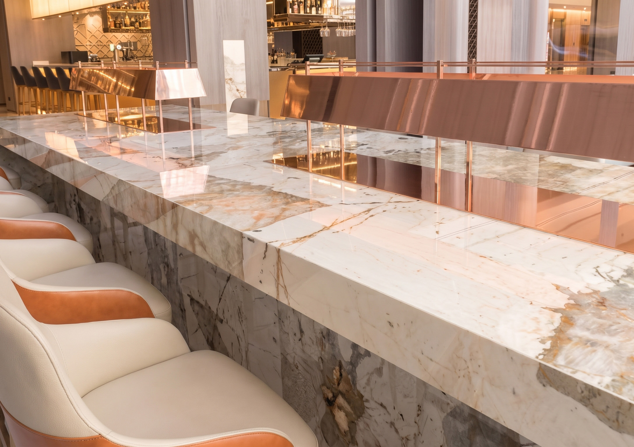 A hotel bar counter in a warm-veined quartz, its top and front in one surface