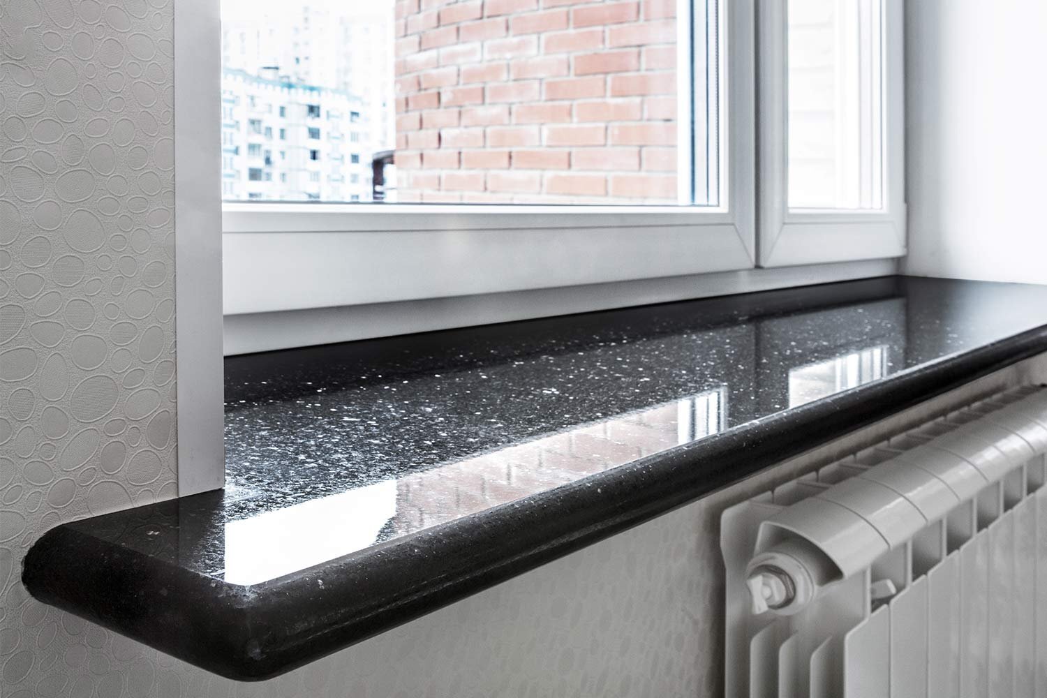 A black granite sill with a rounded front edge above a radiator