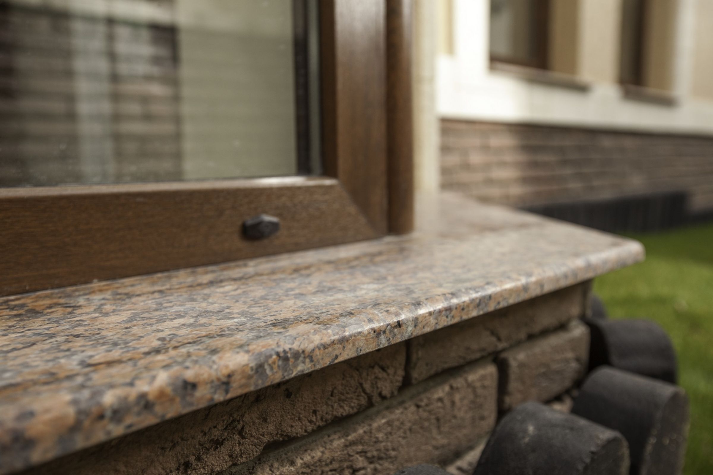 A granite sill outside, under a brown window frame