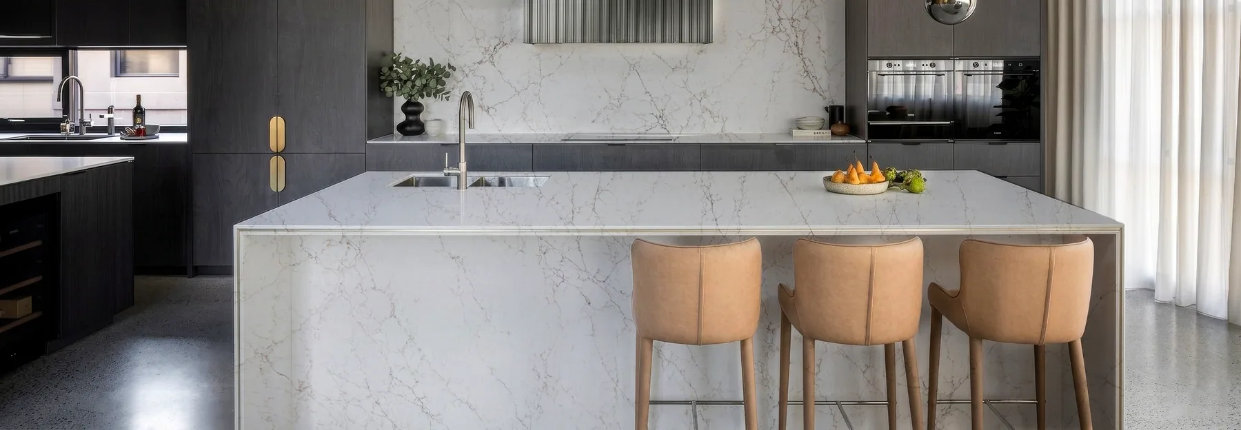 A quartz countertop with an undermount sink and bar stools